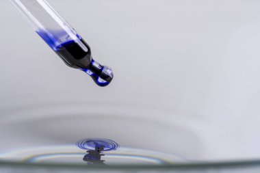 bir pipet ile bir damlacık mavi sıvı