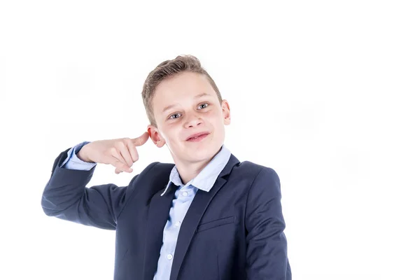 Pojken håller sin hand till sin öra som om han talar i telefon och ser djärvt in i kameran — Stockfoto