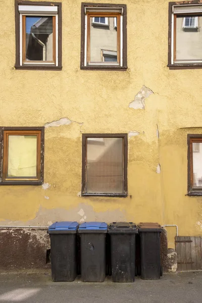 Mülltonnen vor einem alten Haus, dessen Putz bröckelt und abbröckelt — Stockfoto