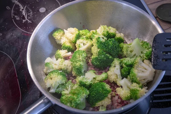 Broccoli is fried in hot oil with bacon cubes — Stock Photo, Image
