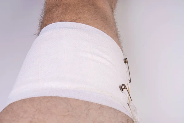 Bandaż dołączony do nogi owłosionej mężczyzny z kołkami bezpieczeństwa — Zdjęcie stockowe