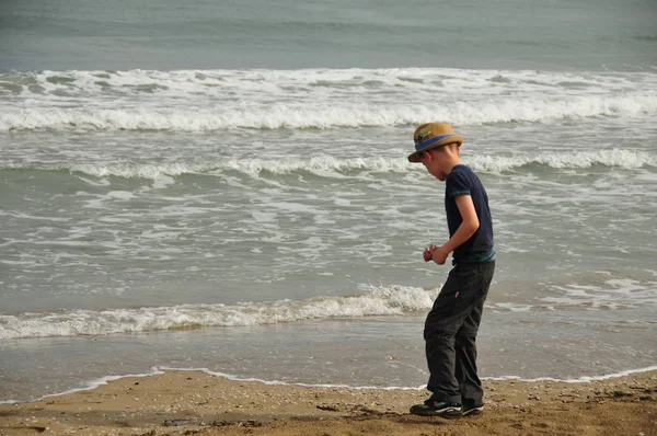 Giovani cerca conchiglie sulla spiaggia di sabbia direttamente in acqua in vacanza — Foto Stock