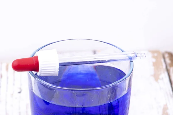 Mavi sıvı ile bir cam üzerinde kırmızı kauçuk Damlasi ile pipet — Stok fotoğraf