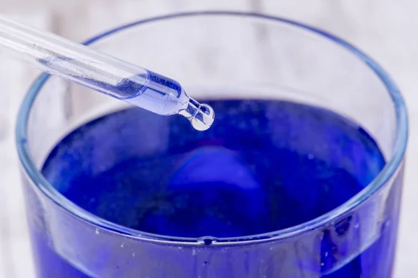 Pipette getta una goccia di liquido in un contenitore di liquido blu — Foto Stock