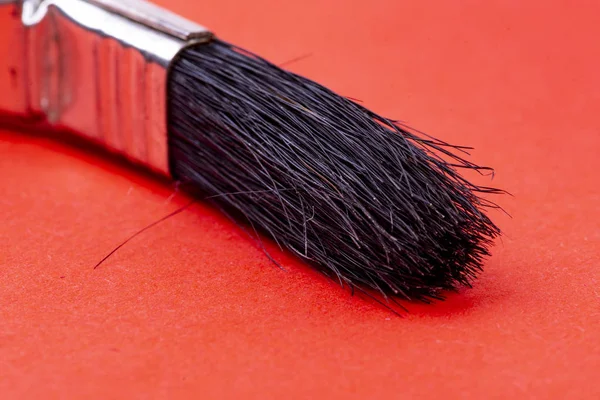 Pinsel für Renovierungen mit schwarzen Borsten auf rotem Hintergrund — Stockfoto
