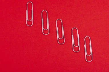 Kırmızı arka plan üzerine yukarıdan ayrı ayrı yerleştirilen ataşlar