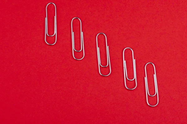 Kırmızı arka plan üzerine yukarıdan ayrı ayrı yerleştirilen ataşlar