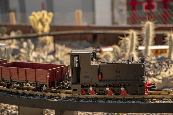 Miniature railway travels over rails in front of a Wild West scenery with cacti