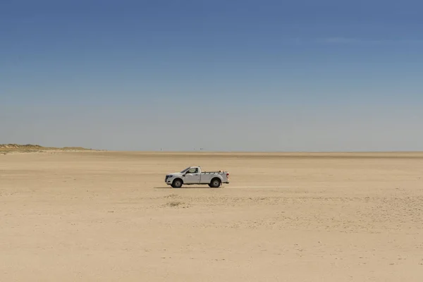 suv alone on an endless beach and a blue sky in the North Sea