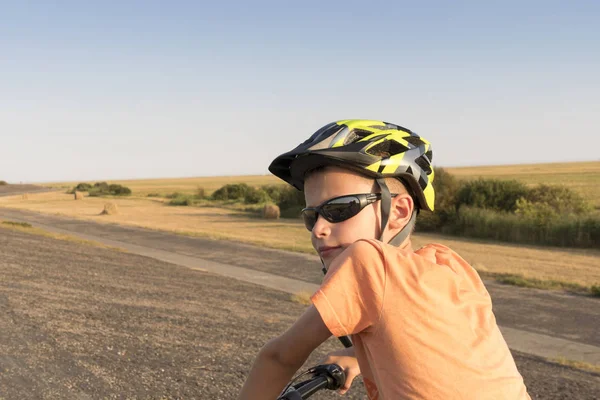 Un niño montado solo en una bicicleta en la presa en el Mar del Norte entre la hierba de caña alta — Foto de Stock