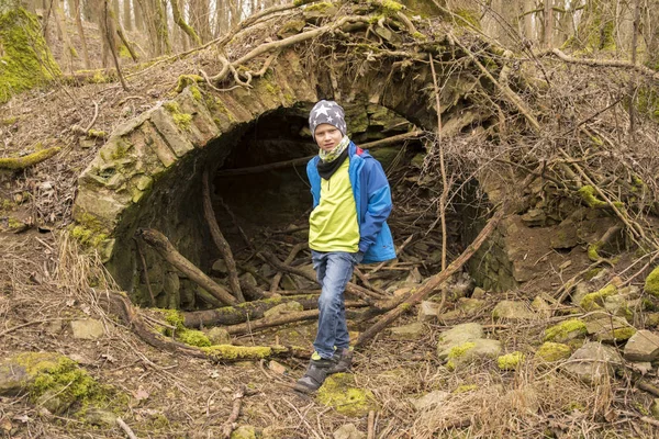 Garçon se tient devant une grotte pendant la géocachette pour chercher un trésor — Photo