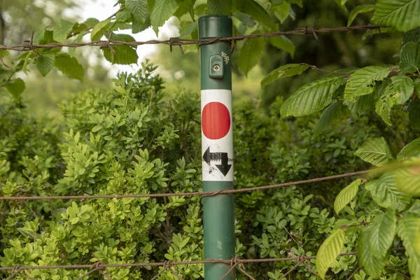 round hiking sign with a red dot and two arrows for the signposts