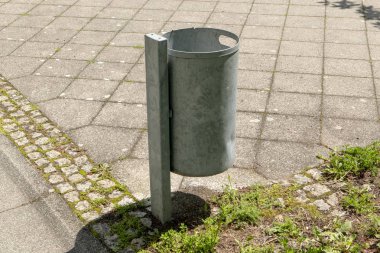 Çim ve kaldırım taşları ile parkta Metal çöp kutusu