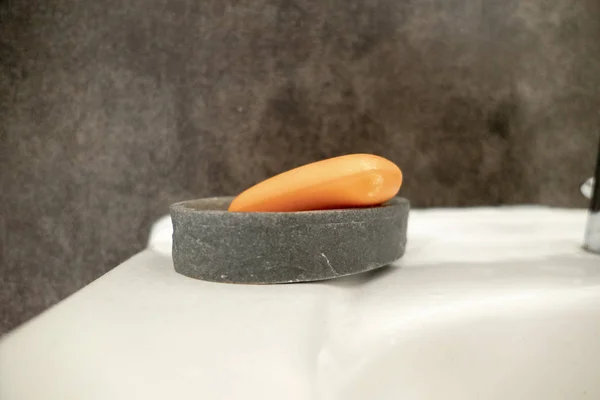 Jabón naranja contra fondo gris en el lavabo en el baño — Foto de Stock