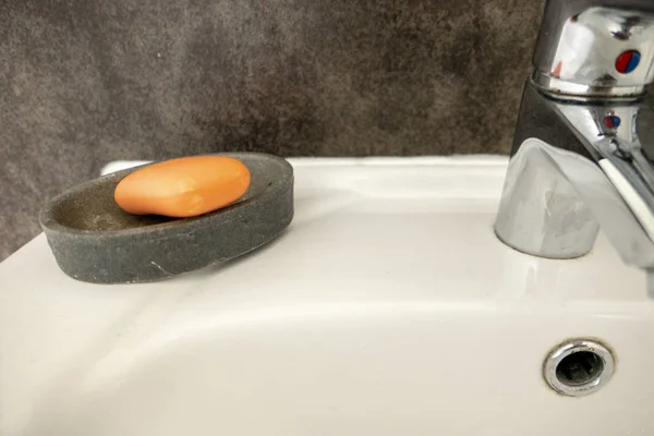orange soap against grey background at the sink in the bath