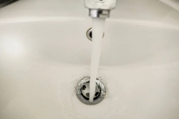 Running water in the sink with football stopper — Stock Photo, Image