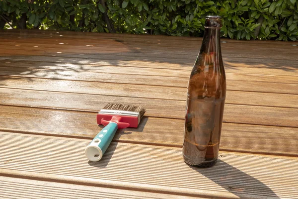 Leere Bierflasche und Pinsel liegen auf der halb eingelassenen Terrasse mit Glasur — Stockfoto