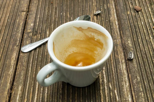 Schmutzige leere Espressotasse auf einem Holztisch mit Kaffeesahne und Löffel — Stockfoto