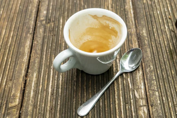 Schmutzige leere Espressotasse auf einem Holztisch mit Kaffeesahne und Löffel — Stockfoto