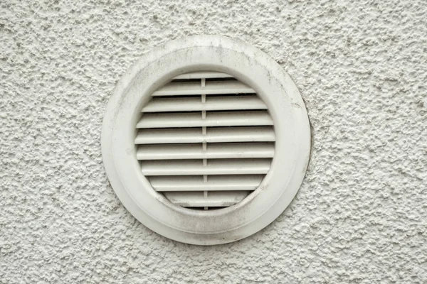 Plastic ventilation outlet on a house wall with air slits and dirt