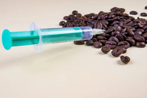 Кофеиновый шприц с кофейными зернами на бежевом — стоковое фото