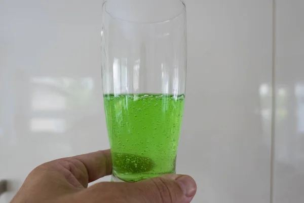 Green viscous liquid in the glass with hand — Stock Photo, Image