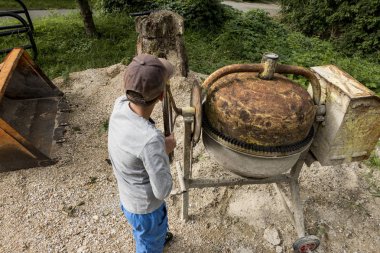 beton için yaşlı ve paslı karıştırıcı ile genç çocuk