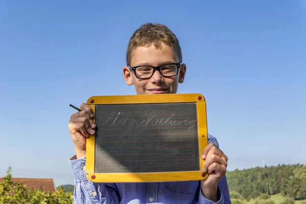 Умный мальчик в очках и доске в "школе зачисления" настаивает перед синим небом — стоковое фото