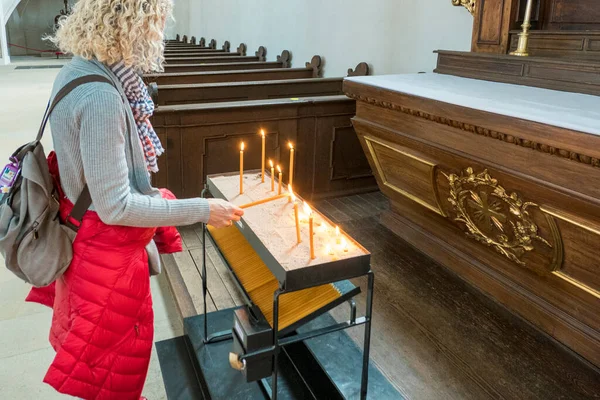 Woman lighting a candle in church for her sins
