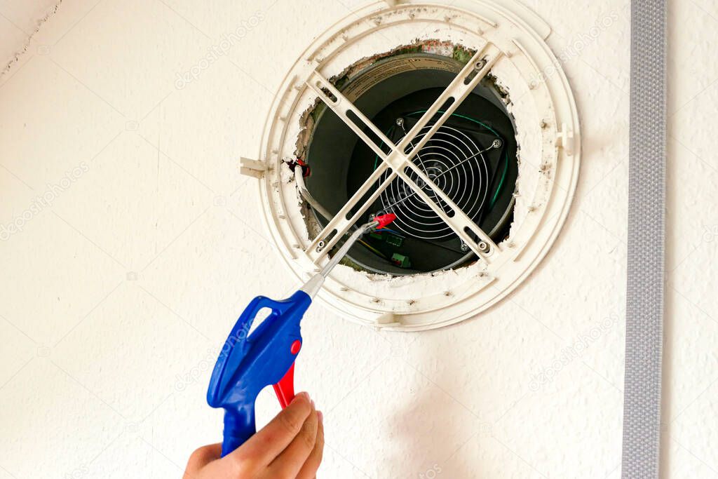 Clean the ventilation system in the room wall in the house with compressed air