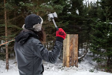 Kış elbiseleri giymiş adam ahşap tahta parçası rekabet atma bir balta gibi önünde bir balta tutar