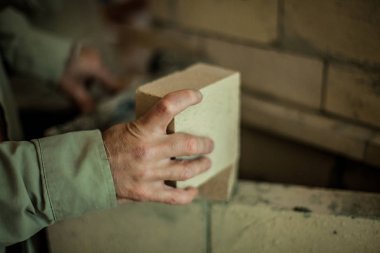 Brickmason'ın el bir tuğla tuğla duvar önünde tutarak