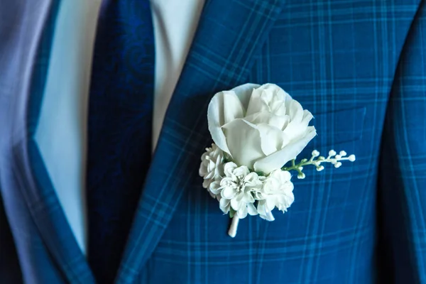 White wedding rose on man\'s fancy blue jacket