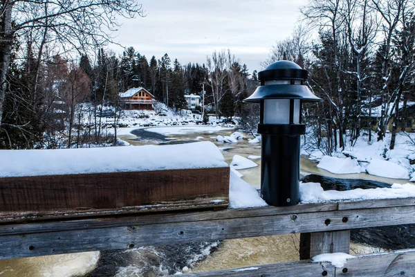 Lantern and frozen planter box in front of a partiallty-frozen fast flowing  river
