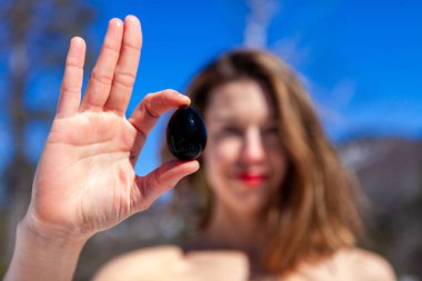 Beautiful woman holds jade egg outdoors. clipart