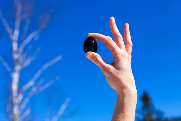 Lady sostiene el huevo de yoni contra el cielo despejado . — Foto de Stock