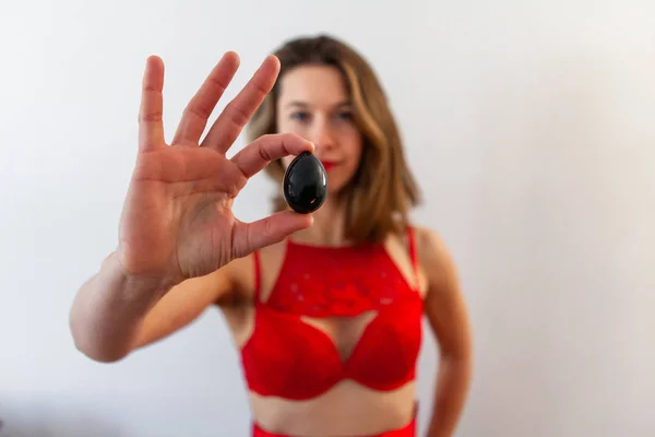 Woman in red lingerie holds jade egg. — Stock Photo, Image