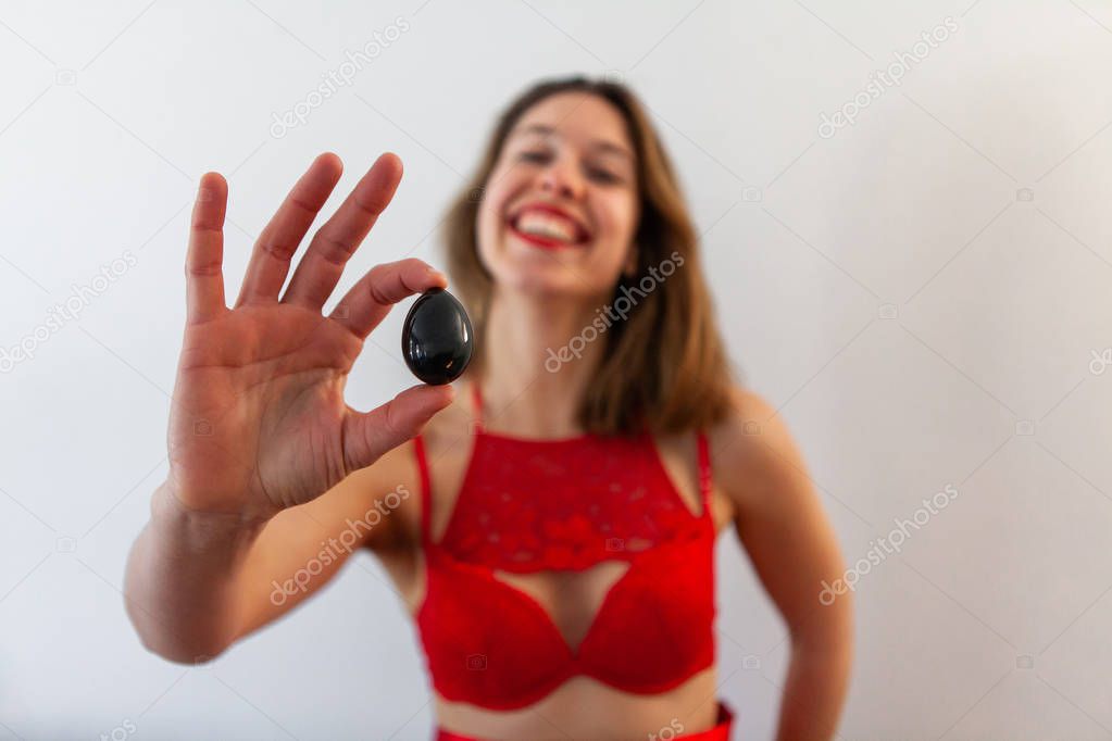 Woman in red lingerie holds jade egg.
