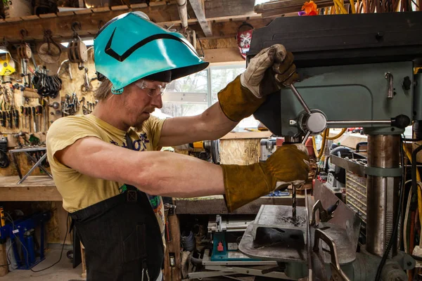 Blacksmith operates bench drill indoors — Stock Photo, Image