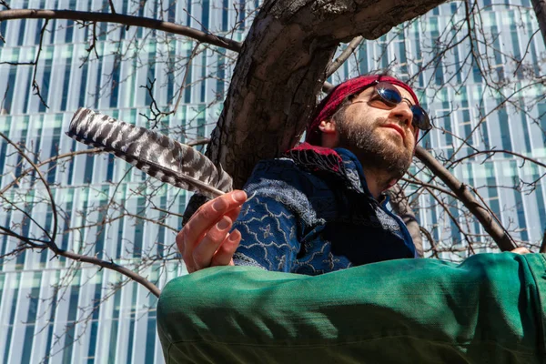 El hombre creativo se sienta en el árbol por rascacielos — Foto de Stock