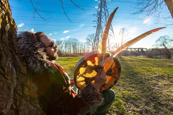Shaman meditates under tree in park