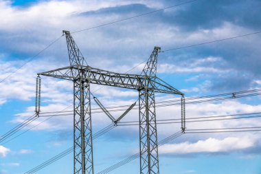 Mavi gökyüzüne karşı elektrik kuleleri.