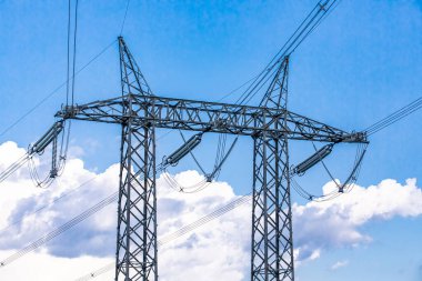 Mavi gökyüzüne karşı elektrik kuleleri.