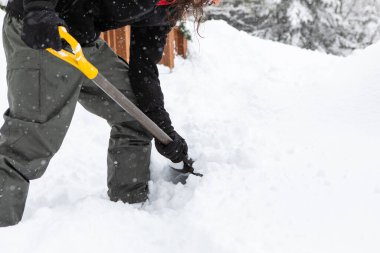 Kar küreklerken elinde kürek tutan adam.