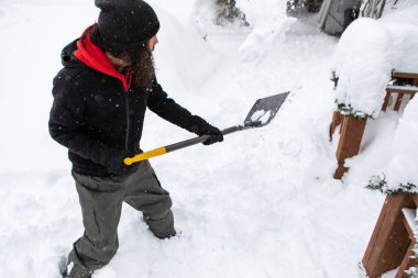 Kar küreklerken elinde kürek tutan adam.