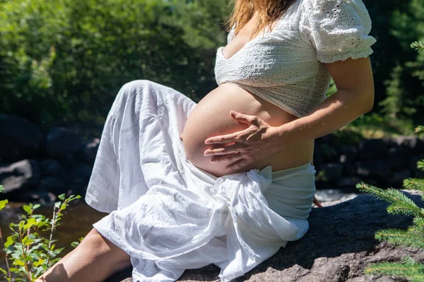 Беременная женщина позирует в лесу — стоковое фото