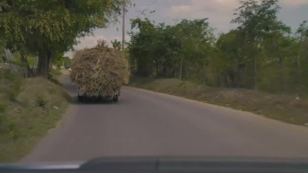 Auto folgt Lkw, der Heu auf Straße transportiert — Stockvideo