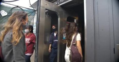 Maskeli insanlar metroya girip çıkıyorlar.