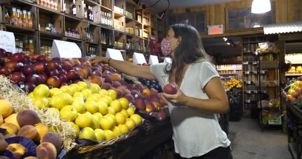 Молода жінка в масці купує продуктовий — стокове відео