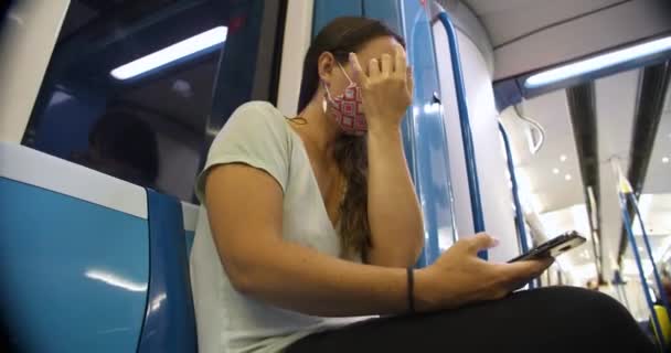 Vrouw met masker zittend in de metro met behulp van telefoon — Stockvideo